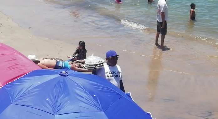 Vendedores de playa en Puerto Vallarta reportan ventas regulares este verano, con turistas regateando sus productos